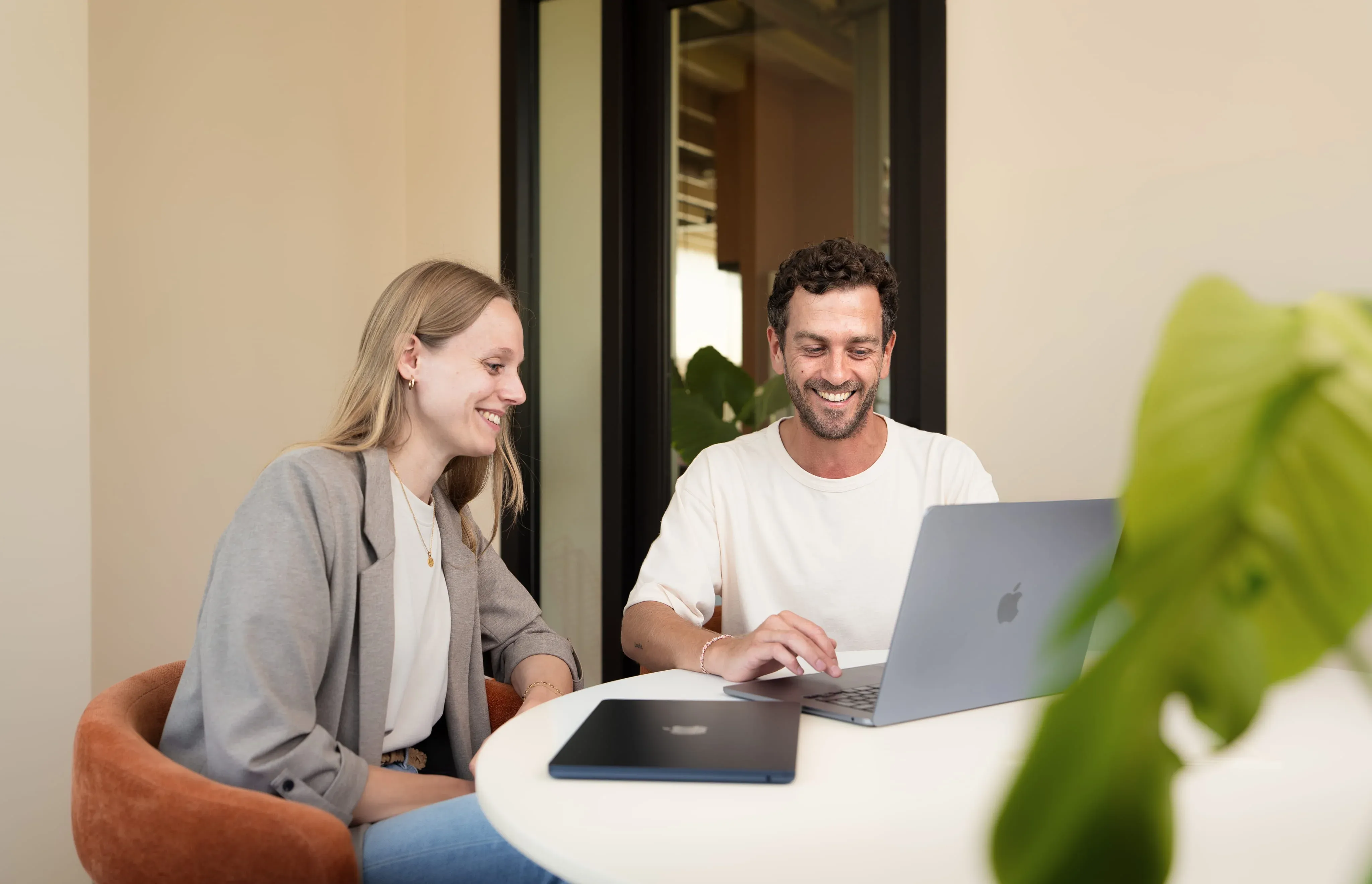 Twee collega's werken samen aan een laptop