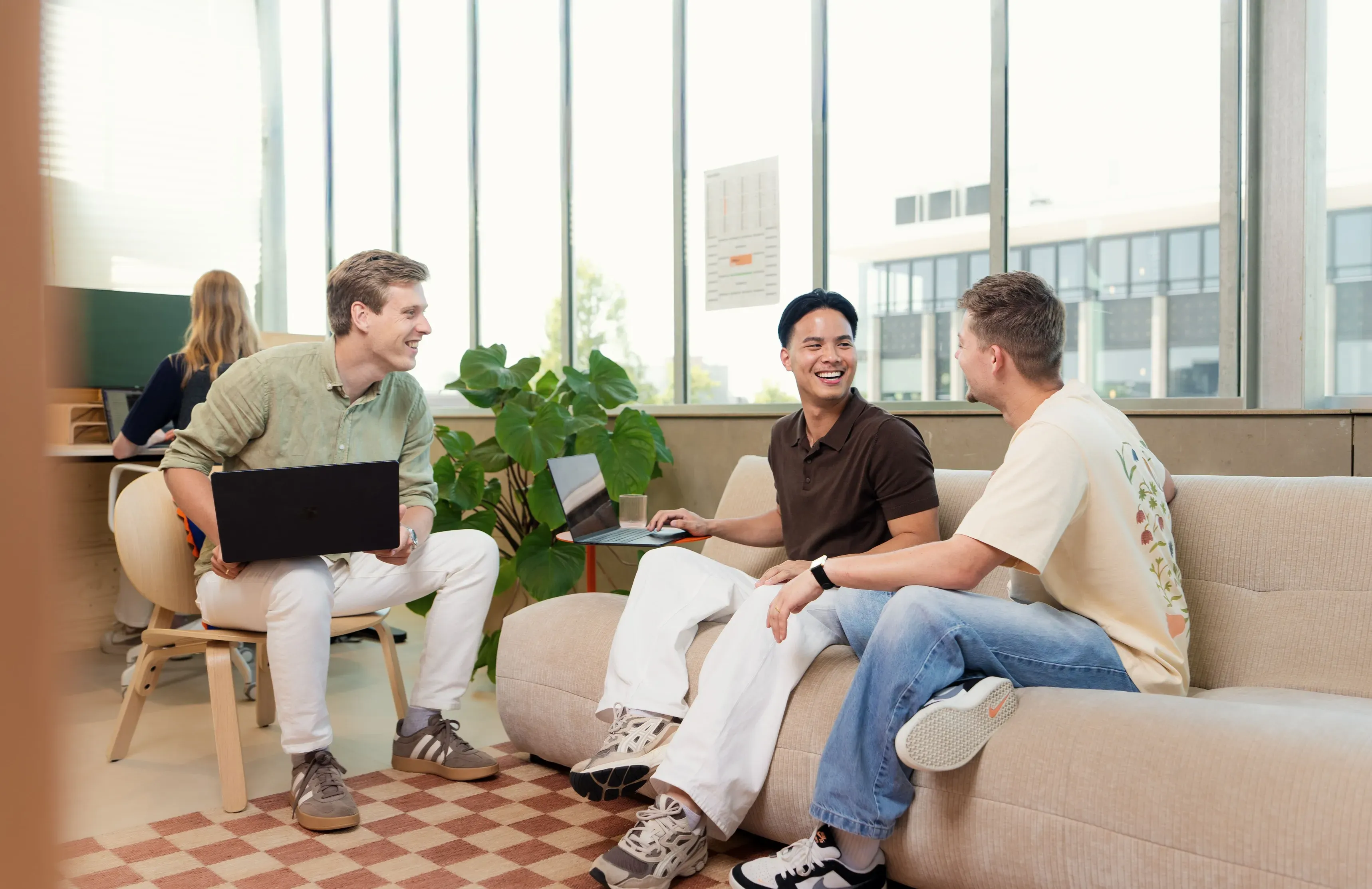 Drie collega's werken op de bank met laptops