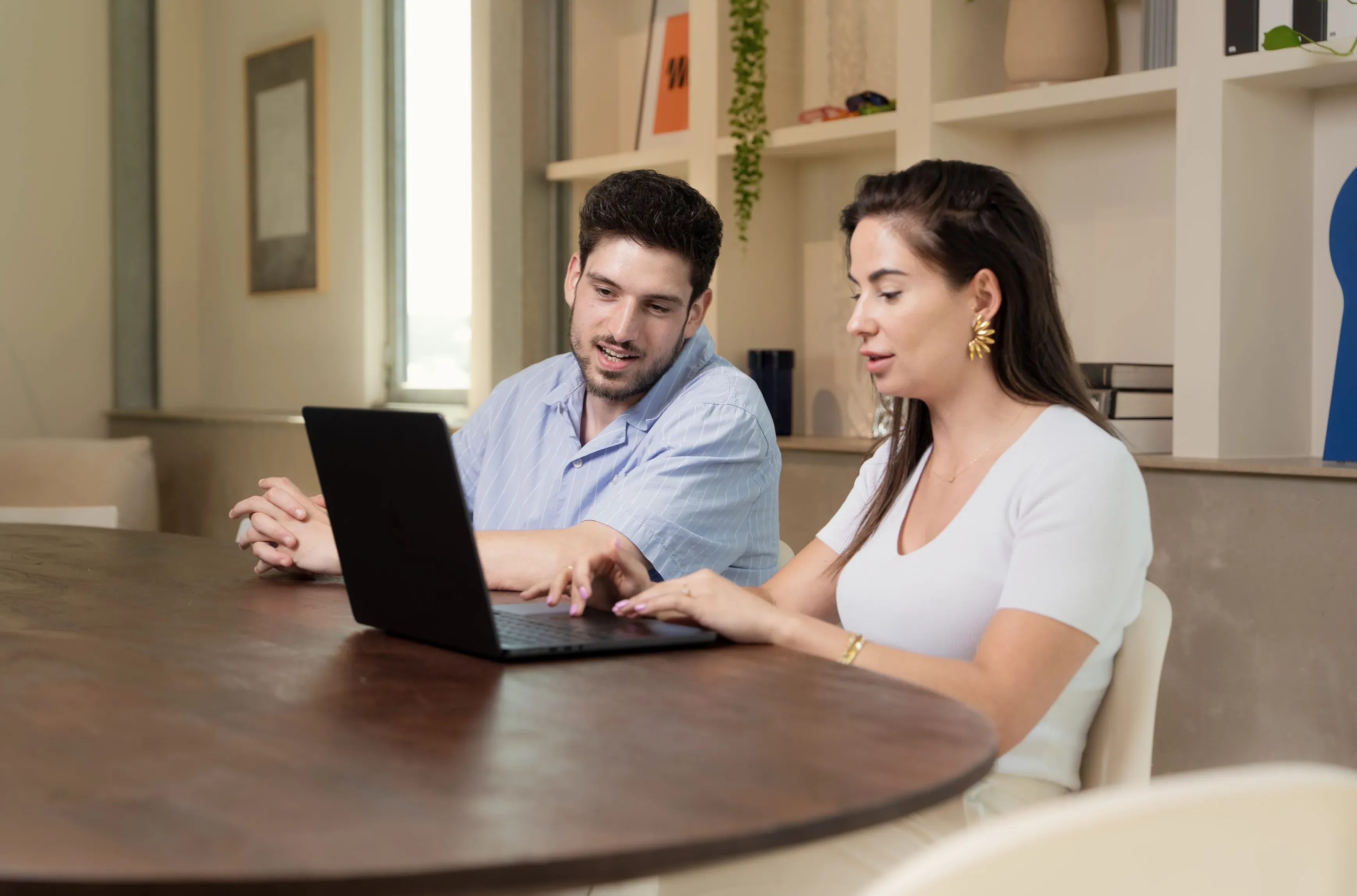 Twee collega's werken aan een laptop aan een ronde tafel