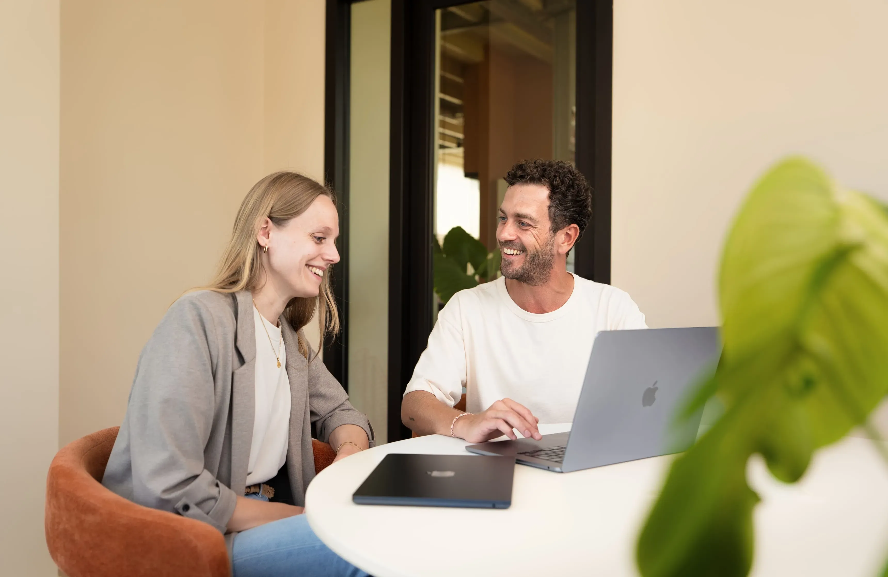 Twee collega's werken samen aan een laptop